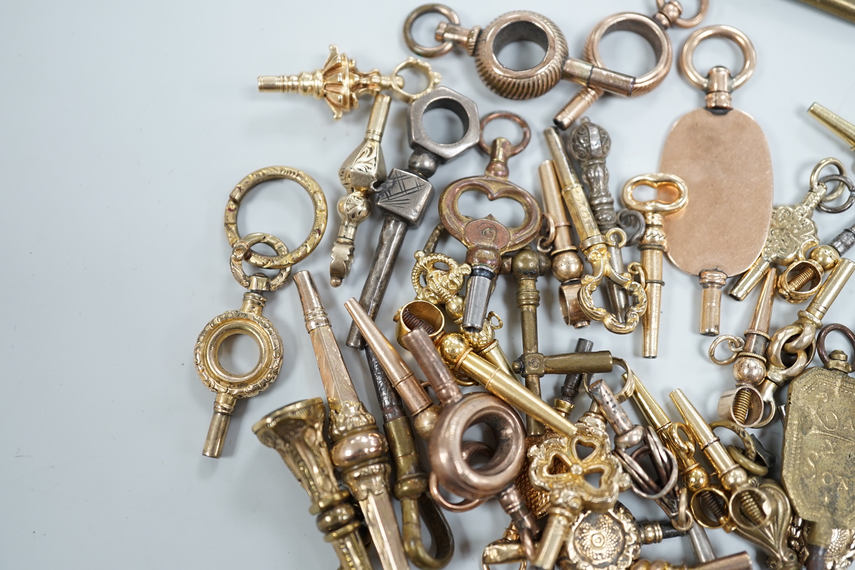 Forty assorted mainly 19th century yellow metal, yellow metal overlaid and base metal small watch keys, including trade insignia and keys for turning in one direction, largest 52mm, together with a limited edition copy,